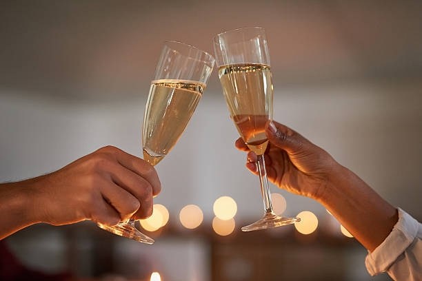 To personer skåler med champagneglass i varm restaurantbelysning